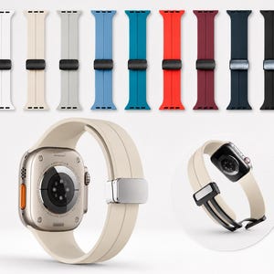 May include: A collection of nine silicone watch bands in various colors including white, beige, gray, blue, teal, red, maroon, navy, and black, each featuring a metallic magnetic clasp. A beige watch band is attached to a smartwatch case.