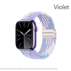 May include: A violet smartwatch with a black screen and a braided elastic band featuring a woven pattern of white, light blue, and lavender threads. The word Violet is printed in the upper right corner above the watch.