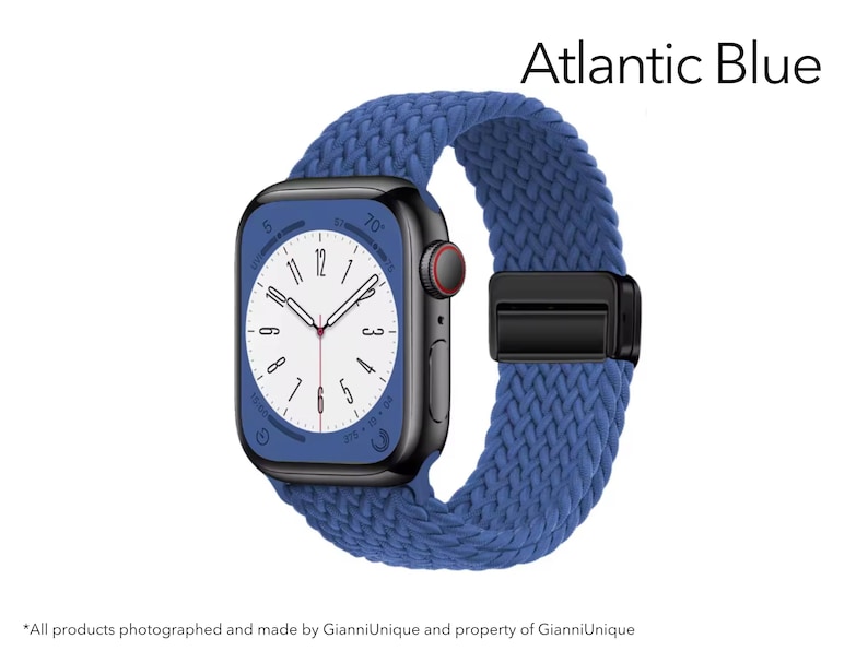 May include: A smartwatch with a black rectangular case and a textured Atlantic Blue braided band. The watch face features a white dial with black numerals and a red-accented crown. The text Atlantic Blue is displayed in the upper right corner.