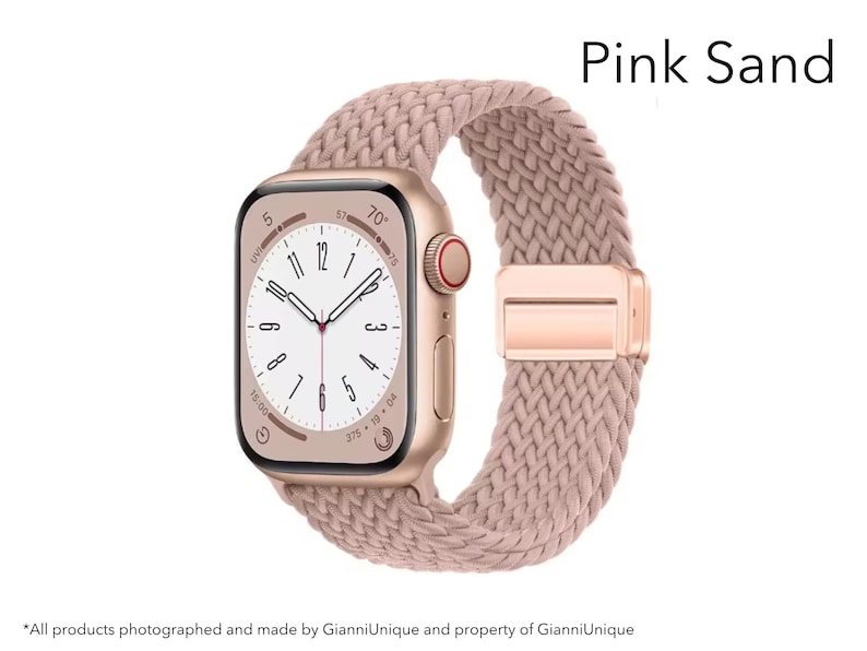 May include: A smartwatch with a rectangular gold-tone case and a pink sand braided band. The watch face displays a white dial with black numerals and hands. The text Pink Sand is visible in the upper right corner of the image.