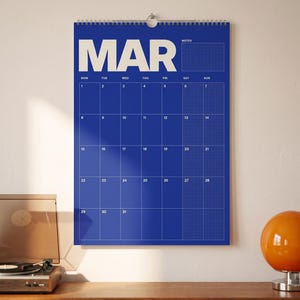 May include: A wall calendar for the month of March featuring a bold blue background with white text and grid lines. The calendar displays the days of the week, dates from 1 to 31, and a dedicated section for notes in the upper right corner.