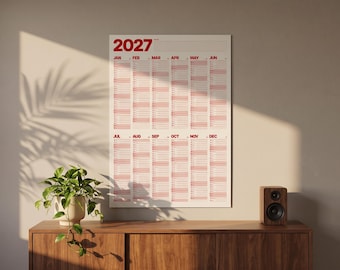 Puede incluir: Un calendario de pared vertical para el año 2027 con fondo blanco y texto en rojo. El calendario muestra los doce meses de enero a diciembre en formato de cuadrícula, con el año 2027 impreso en una fuente roja grande en la esquina superior.