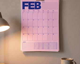 Puede incluir: Un calendario de pared rosa para el mes de febrero con el texto azul en negrita FEB. El calendario presenta una cuadrícula para las fechas del uno al veintiocho, una sección para objetivos y un rastreador de hábitos con filas de círculos.