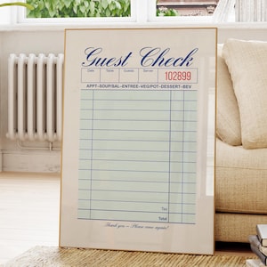 May include: Framed vintage-style "Guest Check" print. The print features a classic design with sections for order details, a unique serial number, and the text "Thank you - Please come again!" in a decorative font. The frame is a light gold colour.