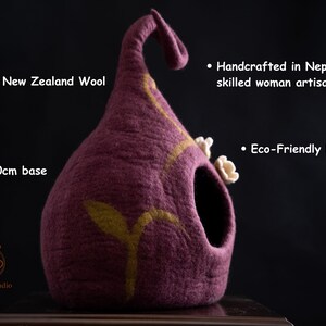 May include: A handcrafted, eco-friendly pet bed made from pure New Zealand wool. The plum-colored bed has a 40cm base, a curved top, and a decorative yellow leaf design. It is handmade in Nepal.