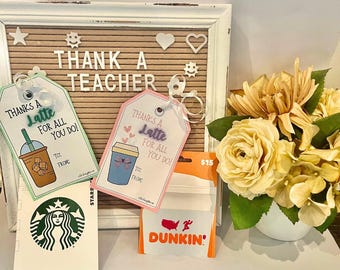 May include: Two gift tags with a coffee cup design and the text "Thanks a Latte for all you do!"  A Dunkin' Donuts gift card with a $15 value. A Starbucks logo and a white board with the text "Thank a Teacher".