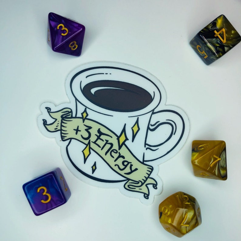 May include: A white coffee mug with a black coffee inside and a banner that says " +3 Energy" in yellow lettering. The mug is surrounded by five dice with gold and purple accents.