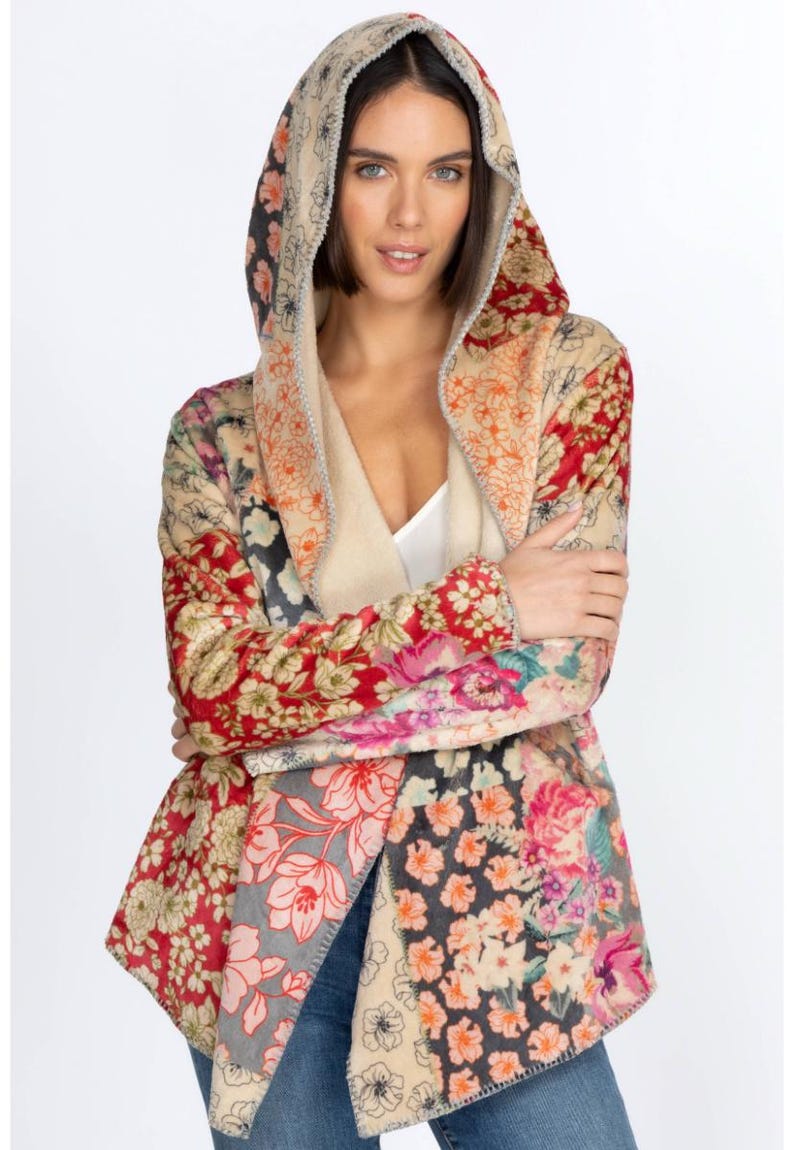 May include: A hooded jacket with a patchwork floral design. The jacket features a variety of floral patterns in shades of red, pink, beige, and gray. The hood is lined with a soft, cream-colored material. The jacket is open in the front and has long sleeves.