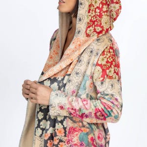 May include: A hooded jacket with a patchwork design featuring floral patterns in various colors. The jacket has a beige interior and a mix of floral prints in red, pink, and blue. The hood is lined with a red floral fabric.