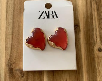 Pendientes de corazón de lucita roja con montura metálica de Zara. Todos los precios incluyen aranceles estadounidenses.