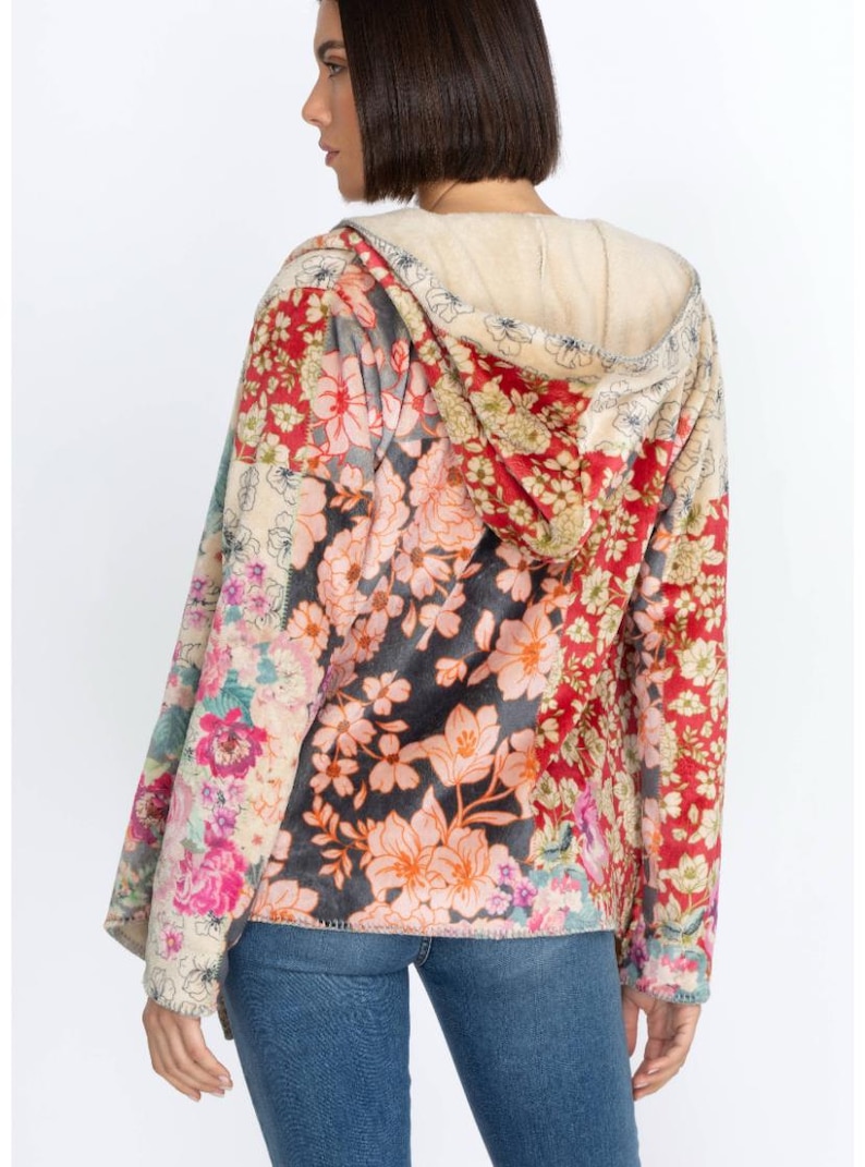 May include: A floral print hoodie with a cream-colored hood lining. The jacket features a patchwork design with various floral patterns in red, pink, and cream colors. The model is wearing blue jeans.