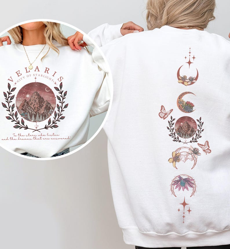 Velaris-themed pink t-shirt with front design of mountains, stars, and 'To the stars who listen' quote. Back highlights moon phases, butterflies, and floral art, blending celestial and fantasy vibes in a stylish, soft fabric.