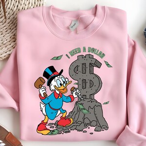 Hilarious Scrooge McDuck money tee for men and women who love cash, wealth, and success. This retro cartoon shirt features the famous duck diving into gold coins, making it a perfect gift for investors, finance lovers, and classic Disney fans!