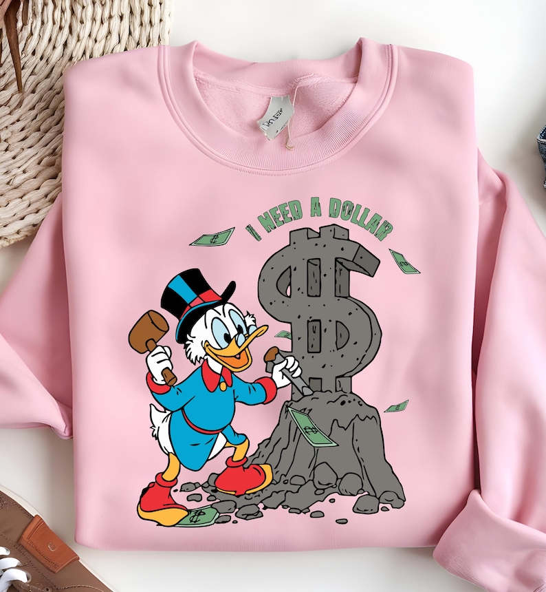Hilarious Scrooge McDuck money tee for men and women who love cash, wealth, and success. This retro cartoon shirt features the famous duck diving into gold coins, making it a perfect gift for investors, finance lovers, and classic Disney fans!