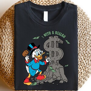 Hilarious Scrooge McDuck money tee for men and women who love cash, wealth, and success. This retro cartoon shirt features the famous duck diving into gold coins, making it a perfect gift for investors, finance lovers, and classic Disney fans!