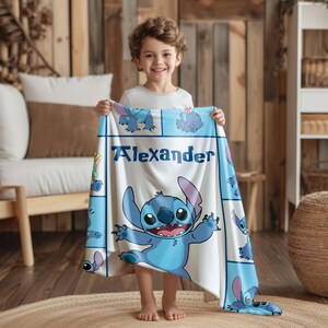 May include: A white blanket featuring the character Stitch from Lilo & Stitch, with the name "Alexander" printed in blue. The blanket has a blue border with Stitch illustrations.
