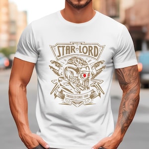May include: White t-shirt with a graphic of Star-Lord from Guardians of the Galaxy. The graphic features a stylized image of Star-Lord's helmet with the text "Star-Lord" and "Smuggler Since 1980".