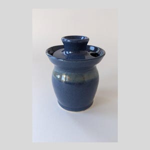 May include: A blue ceramic jar with a lid. The jar has a light blue band around the middle.