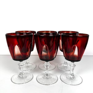 May include: Set of six red wine glasses with clear stems and bases. The glasses have a unique, faceted design.