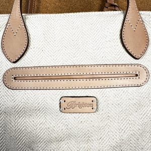 Puede incluir: Primer plano de un bolso tote beige y marr&oacute;n claro. El bolso presenta un patr&oacute;n de espiga, con asas y detalles de cuero marr&oacute;n claro. El nombre de la marca "Brighton" se muestra en una peque&ntilde;a etiqueta de cuero.