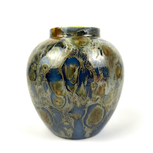 May include: A small, round ceramic vase with a blue and brown marbled glaze. The vase has a wide mouth and a narrow base.