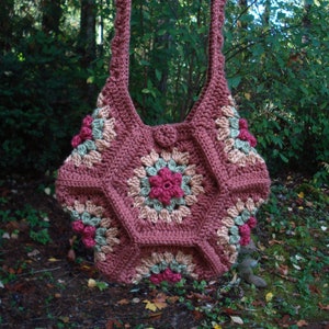 May include: A crocheted shoulder bag with a geometric pattern in shades of brown, pink, and green. The bag has a single strap and a button closure.