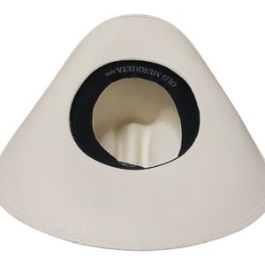 Puede incluir: Sombrero blanco roto con ala ancha y banda interior negra. El interior del sombrero presenta el texto "OLD MURRIETA HATS". El sombrero es de color neutro y tiene un dise&ntilde;o cl&aacute;sico.
