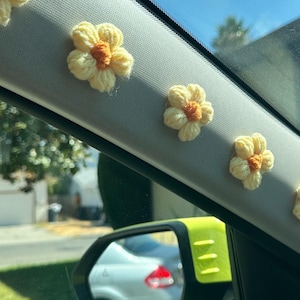 Handmade yellow daisy car decorations adding a cheerful and aesthetic touch to the car interior. Perfect for flower lovers looking for unique car decor or a thoughtful gift idea. Features adhesive backing for easy installation.