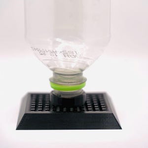 May include: A black plastic water bottle holder with a clear plastic water bottle on top. The bottle holder has a grid pattern and a green ring around the bottle.
