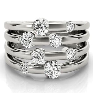 May include: A silver ring with multiple bands and round clear stones set in the bands.
