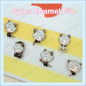May include: A collection of Sylus enamel pins. Each pin features a cartoon character with gray hair and cat ears, wearing a dark red jacket and black pants. The pins are on a yellow and white striped surface, with the text "Sylus Enamel Pin".