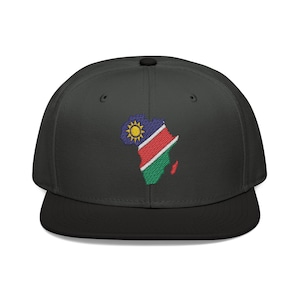 Op de afbeelding: Een zwarte pet met platte klep en zwarte rand. De pet heeft een geborduurd ontwerp van het Afrikaanse continent in de kleuren van de Namibische vlag: blauw, rood, groen en geel. Een stijlvol accessoire.