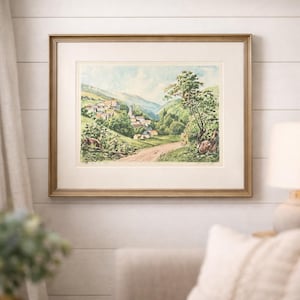 May include: Framed landscape art print featuring a village nestled in a valley. The artwork showcases a dirt road leading towards the village, surrounded by lush green trees and rolling hills. The print is set within a gold-toned frame, adding a touch of elegance to the artwork.