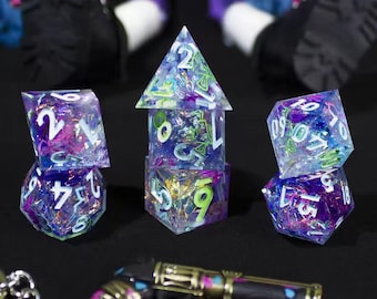 May include: A set of seven polyhedral dice made of translucent resin with embedded iridescent purple, blue, and green foil flakes. The dice feature white engraved numbers. The set includes a d4, d6, d8, d10, d12, d20, and a percentile die.
