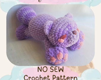May include: A lavender crochet raccoon toy with pink accents on its paws and nose. The soft toy has a textured surface. The image includes the text "Lullaby Raccoon" and "NO SEW Crochet Pattern".