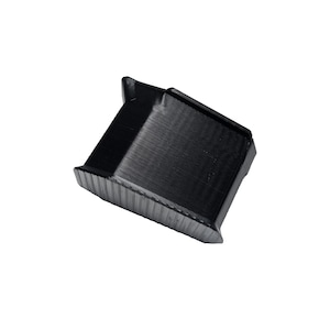 May include: A small, black, angular object with a textured surface. The object has a rectangular shape with a beveled edge and a raised section on one side. The item appears to be made of a solid material.