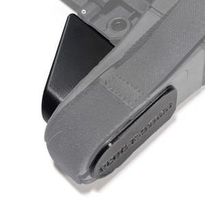 May include: A black camera strap with a black plastic buckle and a gray fabric strap. The strap has the text "Peak Design" printed on it.