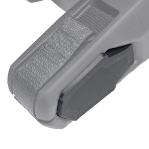 May include: Close-up of a gray plastic component with a textured strap and a dark gray rectangular section. The component has rounded edges and appears to be part of a larger mechanism or device.