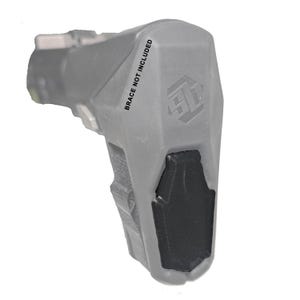 May include: A gray firearm accessory with a black grip. The text "BRACE NOT INCLUDED" is printed on the side. The accessory has a textured surface and a geometric design.