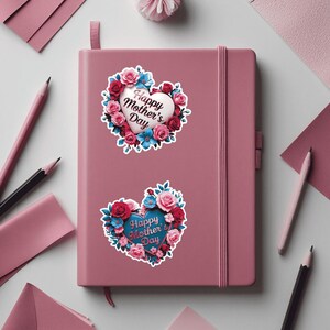 May include: Two pink heart-shaped stickers with floral designs and the text "Happy Mother's Day" on a pink notebook.