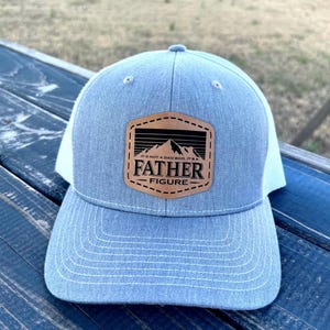 May include: A gray and white trucker hat with a brown leather patch that says "It's not a dad bod, it's a father figure".