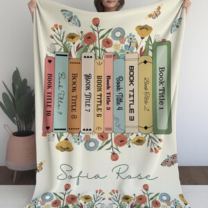 May include: A white throw blanket with a floral design and a row of books with the titles "Book Title 1" through "Book Title 10". The blanket also has the name "Sofia Rose" written in cursive.