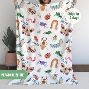 May include: White fleece blanket with a repeating pattern of colorful bugs, butterflies, and the name "Caleb".