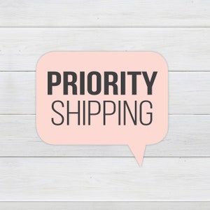 May include: A pink speech bubble with a white outline on a white wood background. The text inside the bubble reads "PRIORITY SHIPPING".