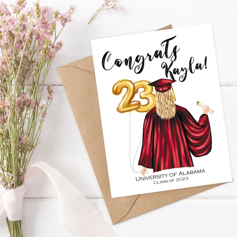 Puede incluir: Tarjeta de graduaci&oacute;n con un globo dorado n&uacute;mero 23, una mujer con una toga de graduaci&oacute;n roja y el texto "Congrats Kayla!" y "University of Alabama Class of 2023".