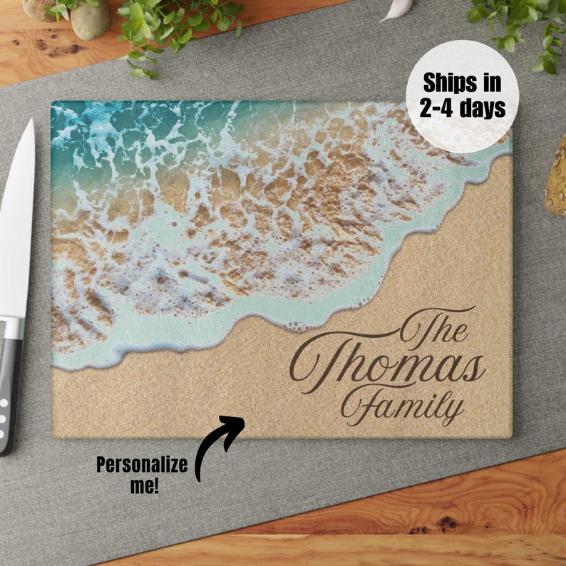 K&ouml;nnte beinhalten: Ein personalisiertes Schneidebrett mit einer Strandszene mit blauem Wasser, wei&szlig;em Schaum und braunem Sand. Der Text "The Thomas Family" ist in Braun auf das Brett gedruckt.