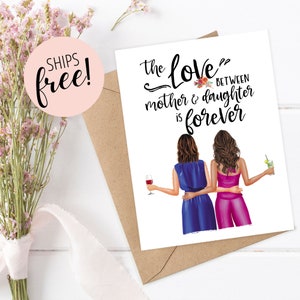 May include: A greeting card with the text "the love between mother & daughter is forever." The card features illustrations of two women, one in blue and one in pink, holding drinks. The card is on a brown envelope.