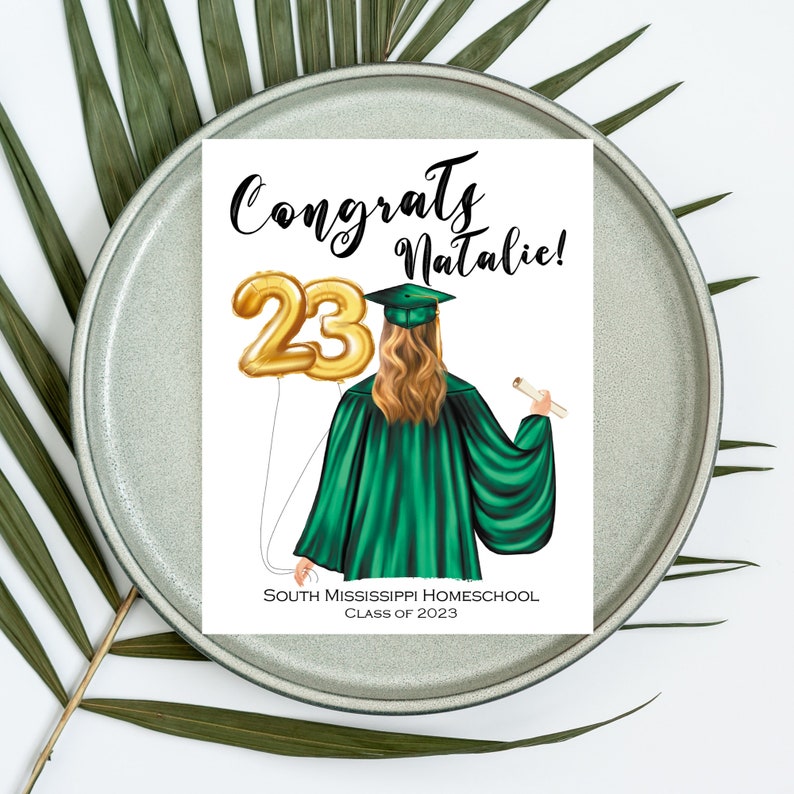 Puede incluir: Una tarjeta de graduaci&oacute;n con una toga y birrete verdes, un globo dorado con el n&uacute;mero 23 y el texto "Congrats Natalie!" y "South Mississippi Homeschool Class of 2023".