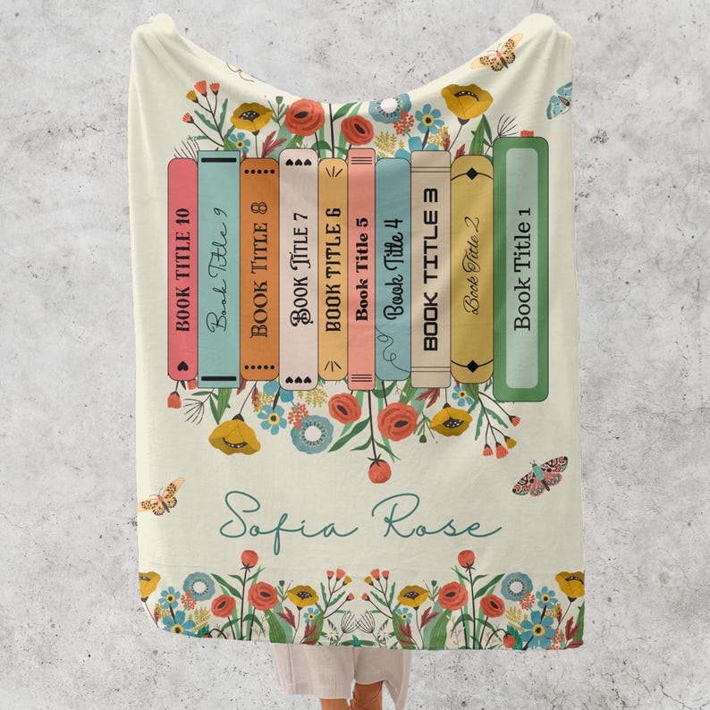 May include: A cream-colored throw blanket with a floral design and a stack of colorful books with the text "Book Title" repeated on each book. The text "Sofia Rose" is written in cursive below the books.