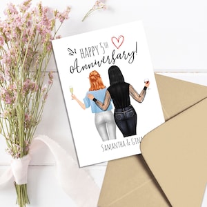 May include: A greeting card with the text "Happy 5th Anniversary!" and the names "Samantha & Gina." The card features an illustration of two people toasting with champagne and wine. A bouquet of pink flowers and a brown envelope are also in the image.